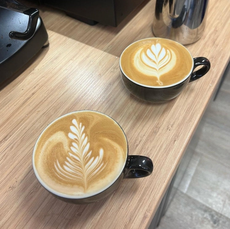 Two beautiful latte art coffees made with Crema coffee beans one of our partner coffee roasters